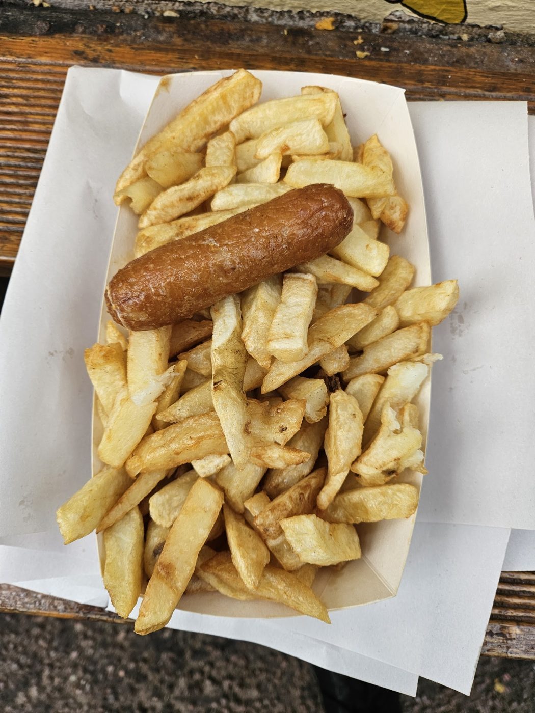 A sausage on a tray of chips